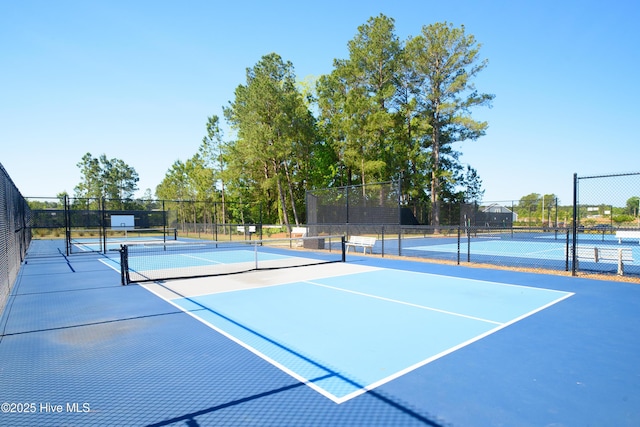 view of tennis court featuring community basketball court and fence