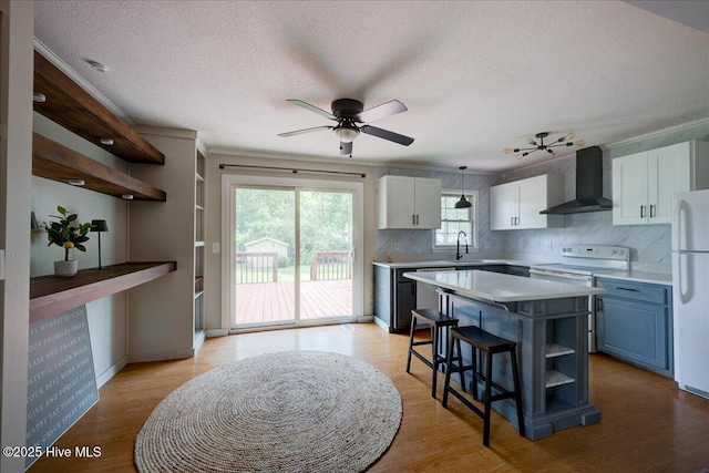 1721 Spencer Ave, New Bern, NC 28560 - kitchen with wall chimney range hood, white appliances, light countertops, a textured ceiling, and a center island