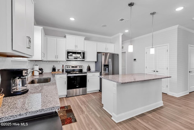 kitchen featuring stainless steel appliances, a sink, light wood-style flooring, ornamental molding, and backsplash