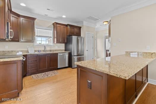 375 Summit Farms Trl, Moyock, NC 27958 - kitchen featuring stainless steel appliances, a peninsula, light wood-type flooring, a sink, and ornamental molding