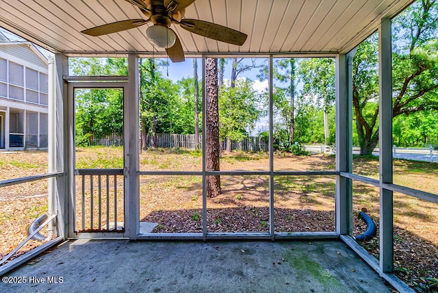 unfurnished sunroom featuring ceiling fan and view of scattered trees