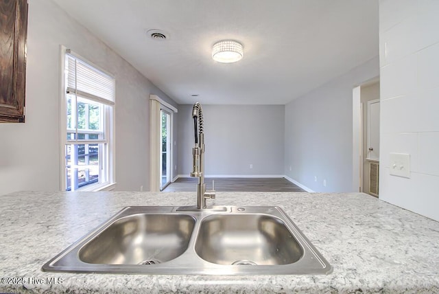 kitchen featuring a sink, dark brown cabinets, light countertops, and wood finished floors