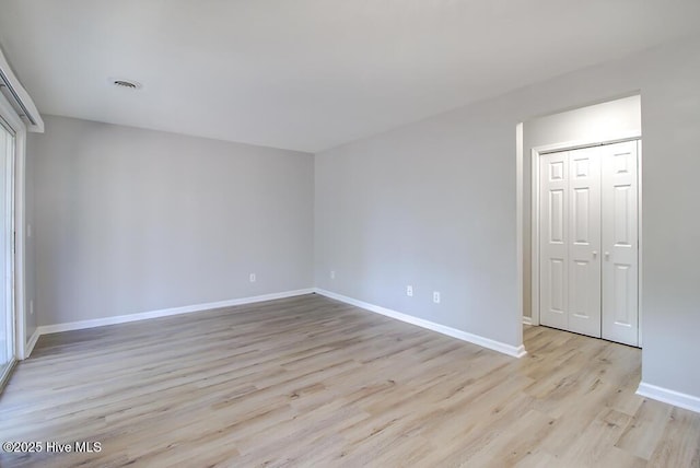 spare room featuring light wood finished floors and baseboards