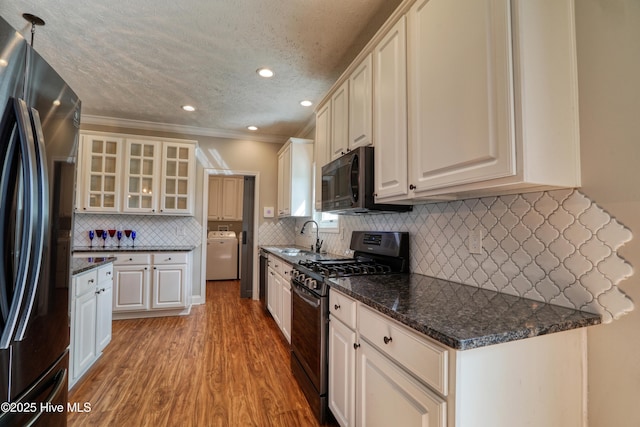 60 Pine Lake Rd, Southport, NC 28461 - kitchen with black appliances, washer / dryer, light wood-style flooring, decorative backsplash, and a sink