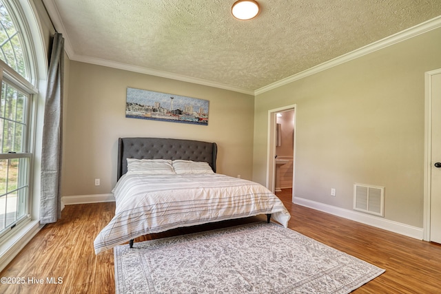 60 Pine Lake Rd, Southport, NC 28461 - bedroom with wood finished floors, a textured ceiling, baseboards, crown molding, and connected bathroom