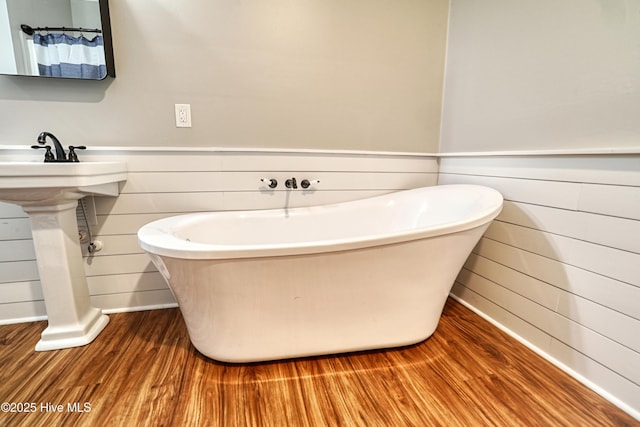 60 Pine Lake Rd, Southport, NC 28461 - bathroom featuring wood finished floors, wood walls, a freestanding bath, and baseboards