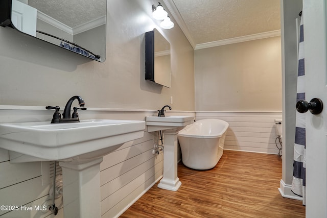 60 Pine Lake Rd, Southport, NC 28461 - bathroom featuring a textured ceiling, crown molding, wood finished floors, a wainscoted wall, and a freestanding tub