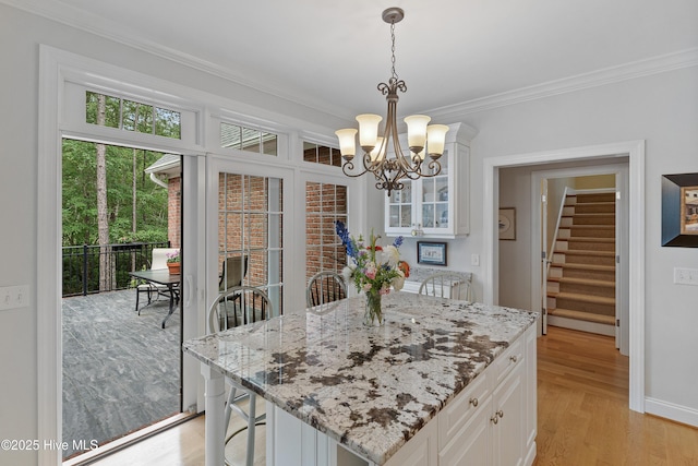 3792 Bancroft Pl, Southport, NC 28461 - kitchen featuring crown molding, a chandelier, white cabinetry, glass insert cabinets, and light stone countertops