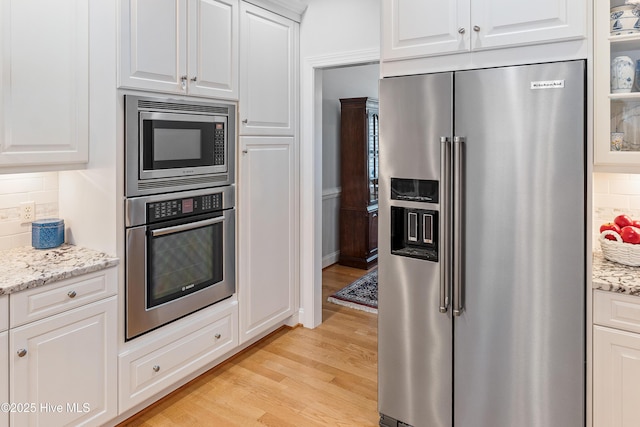 3792 Bancroft Pl, Southport, NC 28461 - kitchen featuring appliances with stainless steel finishes, light wood-type flooring, tasteful backsplash, and white cabinets