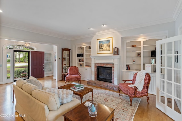 3792 Bancroft Pl, Southport, NC 28461 - living room featuring crown molding, a brick fireplace, light wood-style flooring, built in shelves, and a chandelier