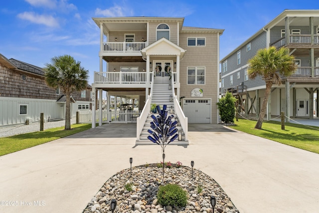 9089 W 9th St, Surf City, NC 28445 - raised beach house featuring concrete driveway, stairs, a garage, a balcony, and a carport