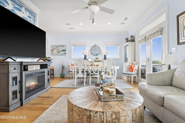 9089 W 9th St, Surf City, NC 28445 - living room with ornamental molding, ceiling fan, a glass covered fireplace, baseboards, and light wood-type flooring