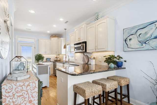 9089 W 9th St, Surf City, NC 28445 - kitchen with appliances with stainless steel finishes, ornamental molding, a peninsula, a sink, and tasteful backsplash