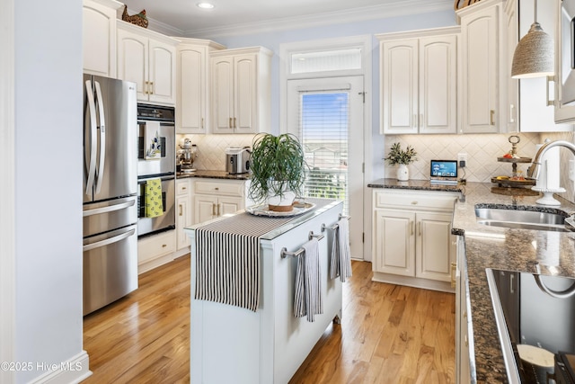 9089 W 9th St, Surf City, NC 28445 - kitchen featuring appliances with stainless steel finishes, a sink, ornamental molding, light wood-style floors, and tasteful backsplash