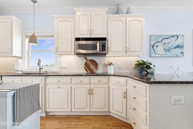9089 W 9th St, Surf City, NC 28445 - kitchen featuring stainless steel microwave, a sink, decorative light fixtures, dark stone countertops, and tasteful backsplash