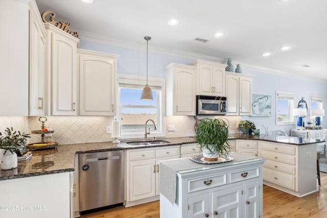 9089 W 9th St, Surf City, NC 28445 - kitchen featuring stainless steel appliances, a sink, ornamental molding, decorative light fixtures, and light wood-style floors