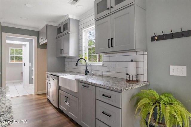 8 Saunders Ln, Pinehurst, NC 28374 - kitchen featuring a sink, stainless steel dishwasher, tasteful backsplash, glass insert cabinets, and light stone counters