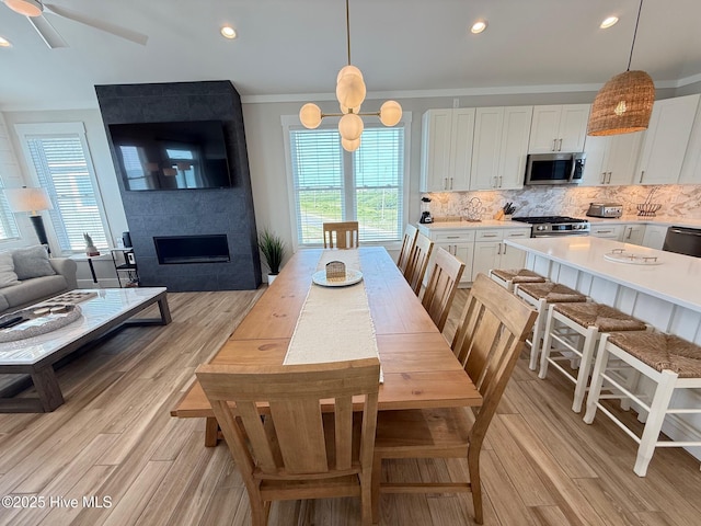 1012 New River Inlet Rd, North Topsail Beach, NC 28460 - dining area featuring light wood finished floors, ornamental molding, recessed lighting, a fireplace, and ceiling fan