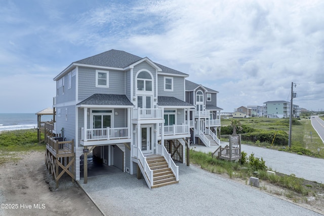 1012 New River Inlet Rd, North Topsail Beach, NC 28460 - coastal home featuring a carport, stairway, roof with shingles, dirt driveway, and a balcony