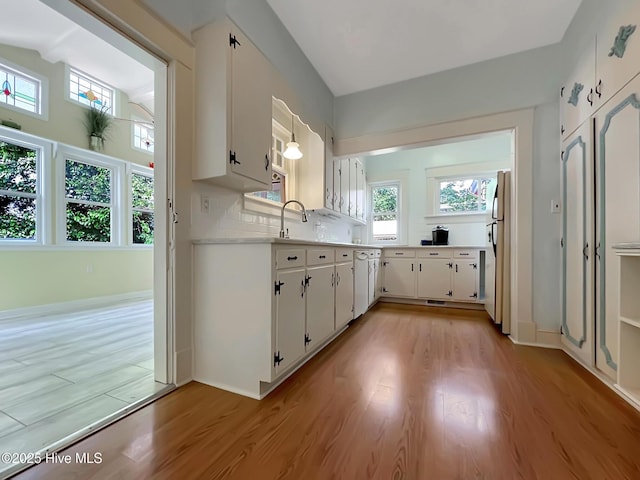 110 Virginia Rd, Edenton, NC 27932 - kitchen featuring freestanding refrigerator, light countertops, light wood finished floors, white cabinets, and tasteful backsplash