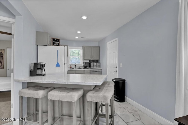 323 Cape Fear Blvd, Wilmington, NC 28401 - kitchen featuring freestanding refrigerator, gray cabinets, a sink, a breakfast bar area, and light countertops