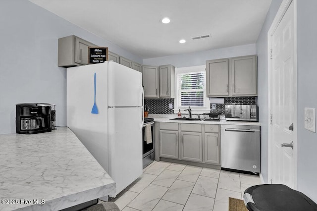 323 Cape Fear Blvd, Wilmington, NC 28401 - kitchen featuring appliances with stainless steel finishes, gray cabinets, a sink, light marble finish floors, and tasteful backsplash