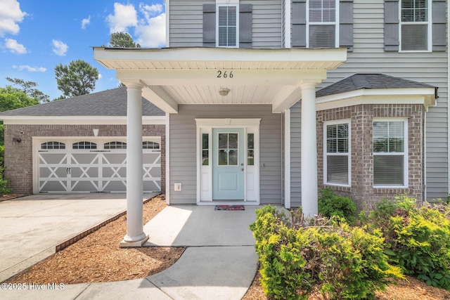 266 Marsh Haven Dr, Sneads Ferry, NC 28460 - view of exterior entry with concrete driveway, an attached garage, and roof with shingles