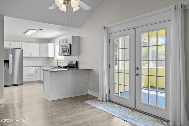 120 NW 19th St, Oak Island, NC 28465 - kitchen with appliances with stainless steel finishes, french doors, a peninsula, decorative backsplash, and white cabinetry