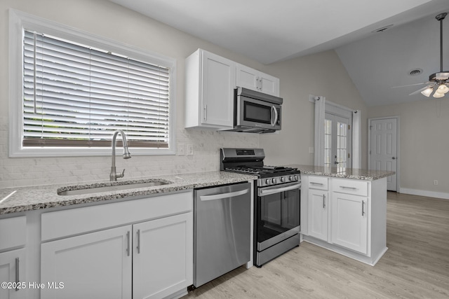 120 NW 19th St, Oak Island, NC 28465 - kitchen featuring appliances with stainless steel finishes, a sink, a peninsula, a ceiling fan, and white cabinets
