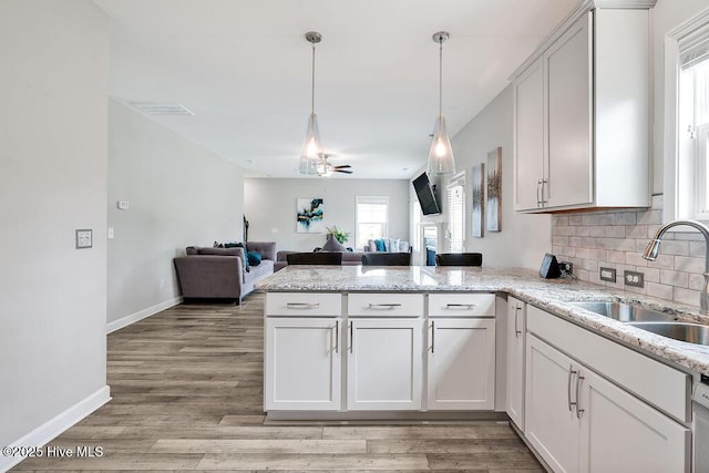 2610 Longleaf Pine Cir, Leland, NC 28451 - kitchen with a peninsula, a sink, open floor plan, baseboards, and backsplash