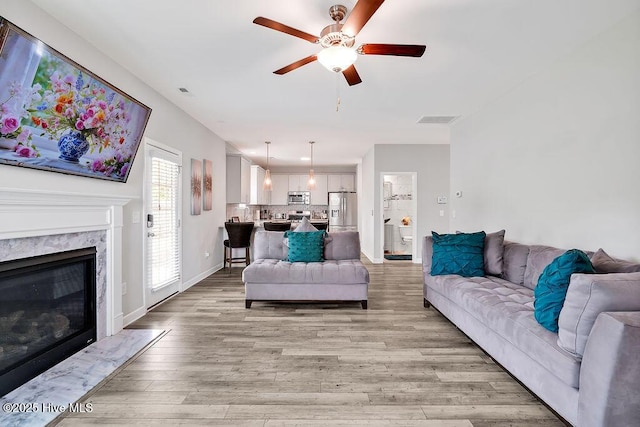 2610 Longleaf Pine Cir, Leland, NC 28451 - living area featuring a ceiling fan, light wood finished floors, a fireplace, and baseboards