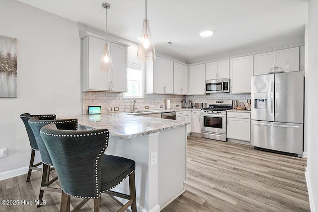 2610 Longleaf Pine Cir, Leland, NC 28451 - kitchen featuring stainless steel appliances, a peninsula, a sink, light stone countertops, and a kitchen breakfast bar