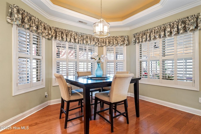 2215 Villamar Dr, Leland, NC 28451 - dining room with a tray ceiling, a chandelier, wood finished floors, crown molding, and baseboards