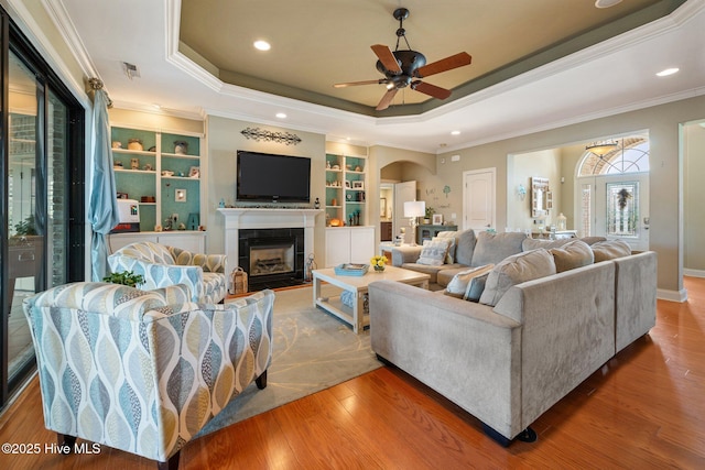 2215 Villamar Dr, Leland, NC 28451 - living area featuring a raised ceiling, ornamental molding, a tile fireplace, ceiling fan, and built in shelves
