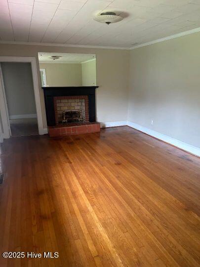 302 N Main St, Robersonville, NC 27871 - unfurnished living room with ornamental molding, a brick fireplace, wood finished floors, and baseboards