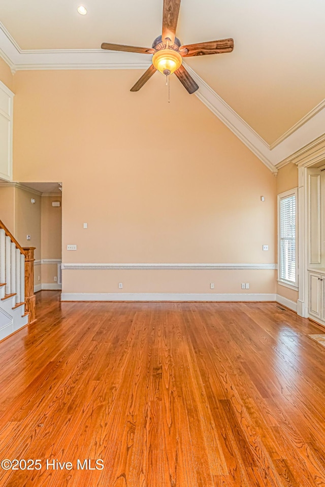 empty room featuring crown molding, ceiling fan, stairway, light wood finished floors, and baseboards