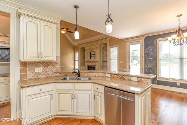 kitchen featuring stainless steel dishwasher, a sink, lofted ceiling, cream cabinetry, and a chandelier