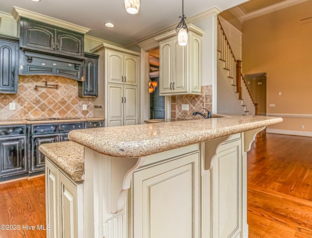 kitchen featuring ornamental molding, light wood-style flooring, a kitchen bar, backsplash, and a peninsula