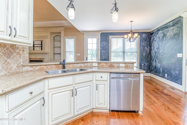 kitchen featuring stainless steel dishwasher, a sink, light wood-type flooring, a chandelier, and hanging light fixtures