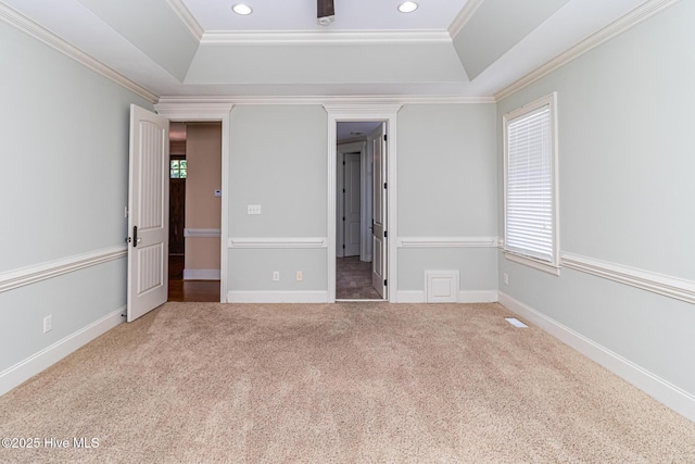unfurnished bedroom featuring a tray ceiling, carpet flooring, multiple windows, ornamental molding, and recessed lighting
