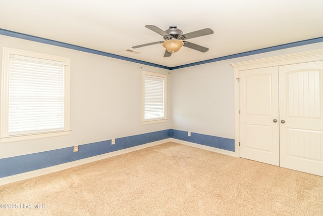 unfurnished bedroom with carpet floors, baseboards, a closet, and a ceiling fan