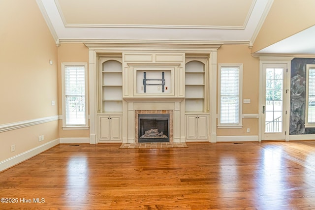 unfurnished living room featuring ornamental molding, wood finished floors, a tile fireplace, and baseboards