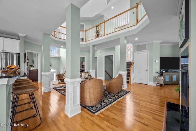 208 Sea Manor Dr, Surf City, NC 28445 - entryway with light wood-type flooring, stairs, ornamental molding, a high ceiling, and ornate columns