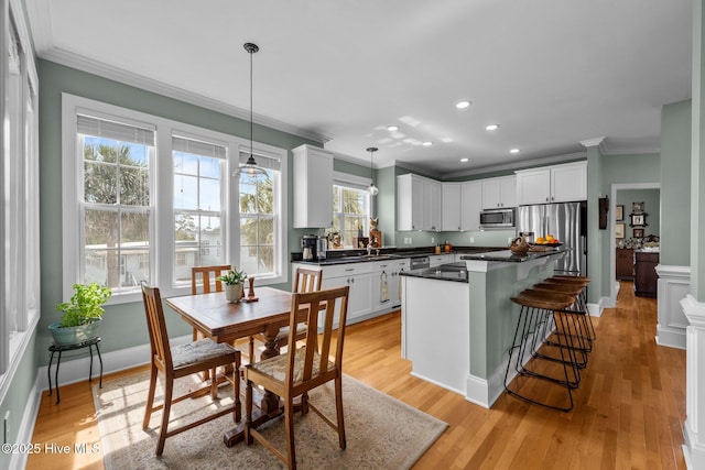 208 Sea Manor Dr, Surf City, NC 28445 - kitchen featuring appliances with stainless steel finishes, crown molding, dark countertops, white cabinetry, and decorative light fixtures