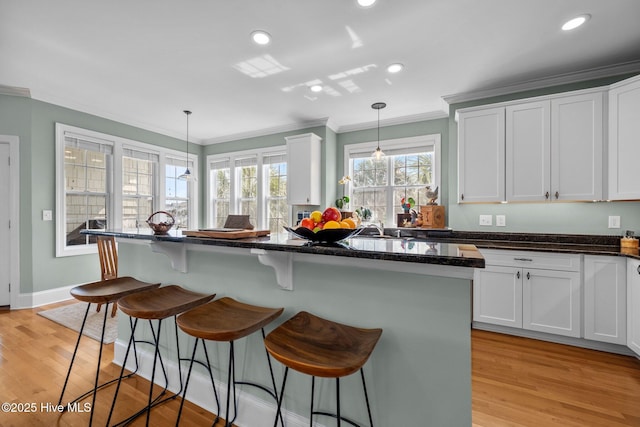 208 Sea Manor Dr, Surf City, NC 28445 - kitchen with white cabinetry, ornamental molding, light wood-style flooring, decorative light fixtures, and recessed lighting