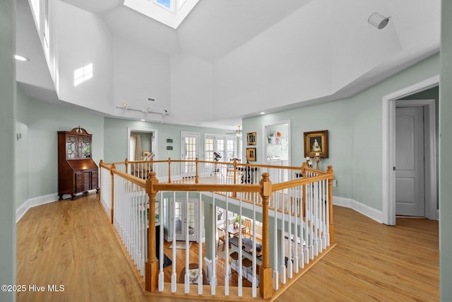 208 Sea Manor Dr, Surf City, NC 28445 - corridor featuring a skylight, high vaulted ceiling, an upstairs landing, light wood finished floors, and baseboards
