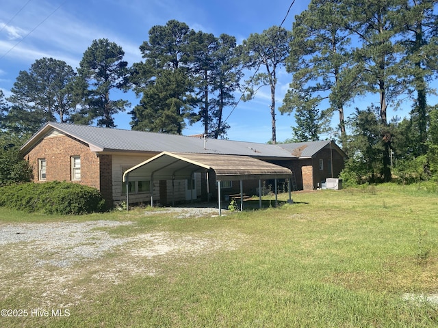 691 Wade Daughtry Rd, Faison, NC 28341 - rear view of house featuring brick siding, a carport, a lawn, and metal roof