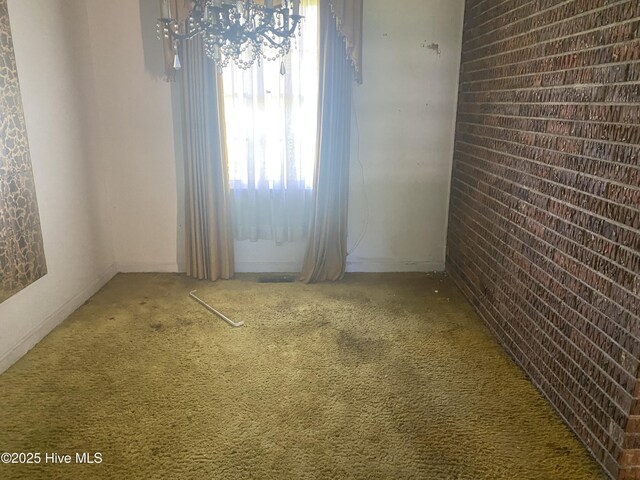 691 Wade Daughtry Rd, Faison, NC 28341 - carpeted empty room featuring brick wall and a chandelier