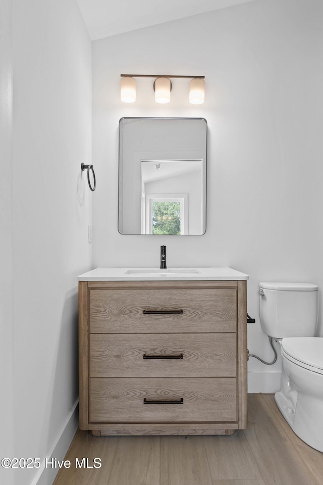 1100 S Sixth St, Carolina Beach, NC 28428 - bathroom featuring baseboards, wood finished floors, toilet, and vanity
