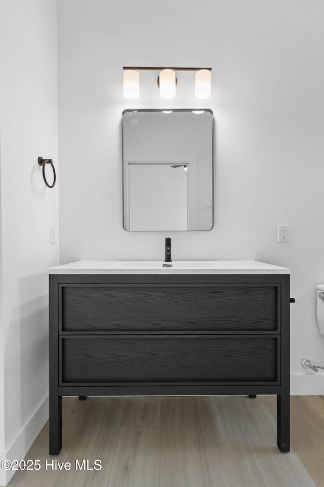 1100 S Sixth St, Carolina Beach, NC 28428 - bathroom with vanity, wood finished floors, baseboards, and toilet
